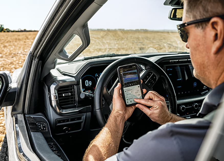 Person operating tractor autonomously using cell phone