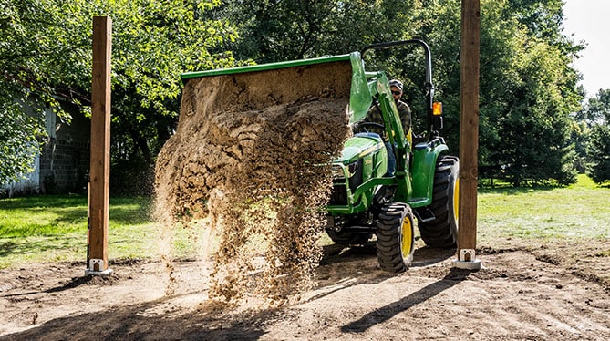 Tractor with loader dumping sand between two posts Tractor with loader dumping sand between two posts