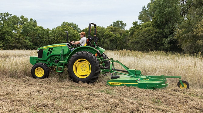 5050E tractor with attachment mowing through tall grass 5050E tractor with attachment mowing through tall grass