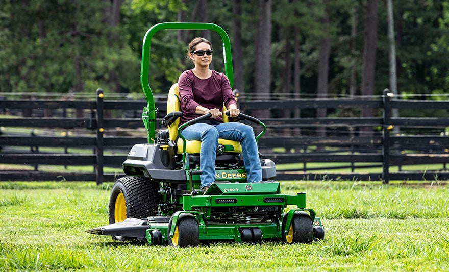 A person riding on a ztrak mower mowing the grass A person riding on a ztrak mower mowing the grass