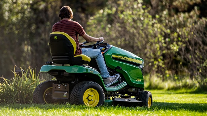 A person riding on a ztrak mower mowing the grass A person riding on a ztrak mower mowing the grass