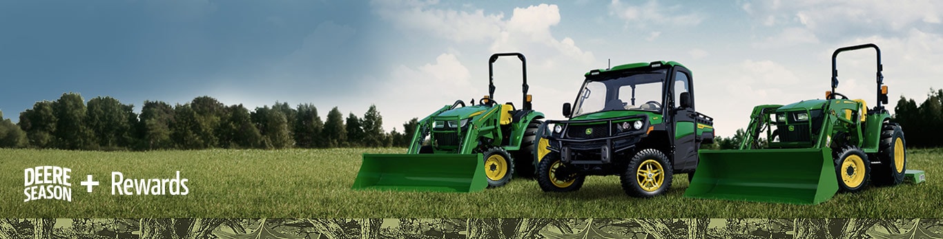 Lineup of two John Deere tractors and a Gator Utility Vehicle on grass in an open field.