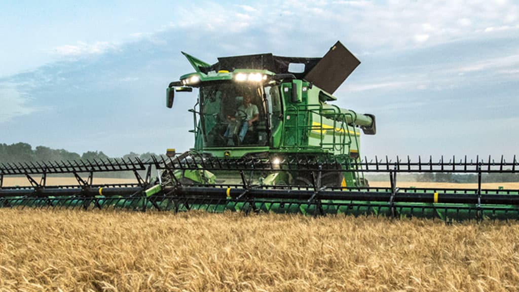 Photo of the front of a John&nbsp;Deere S7 Combine harvesting wheat with a draper head.