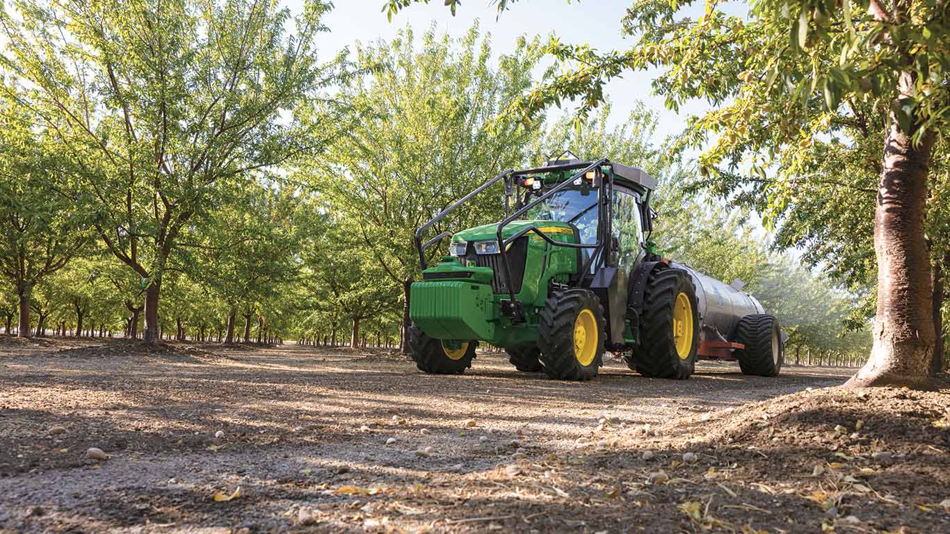 John Deere Tractor pulling a sprayer through an orchard