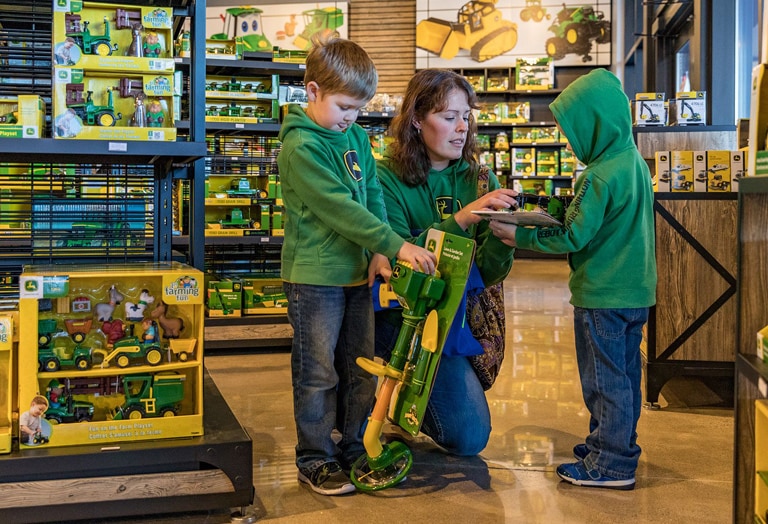 Two children with their mother shopping at a John Deere store