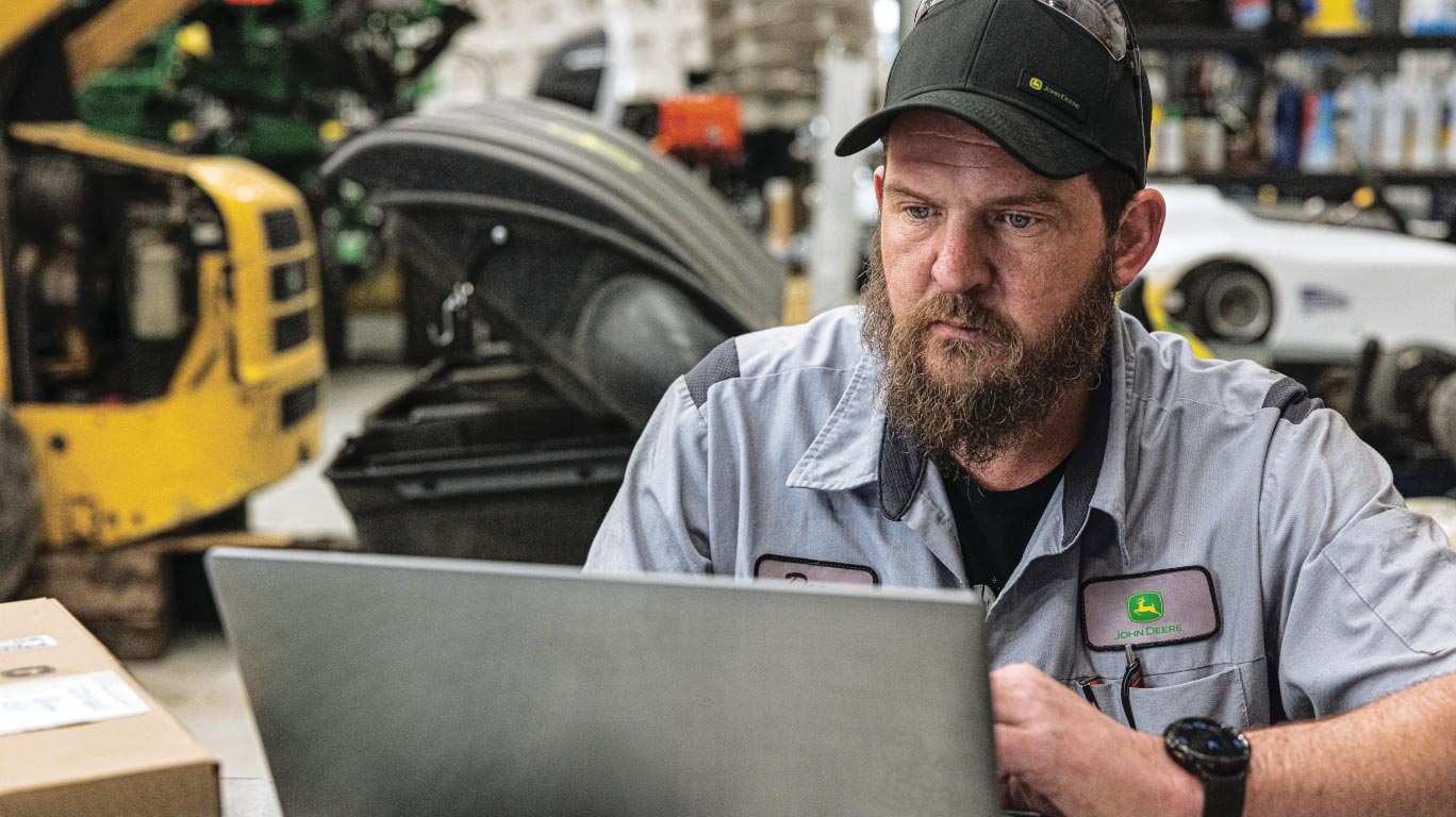 Customer reviewing John Deere Financial account statements on a laptop in a work environment.