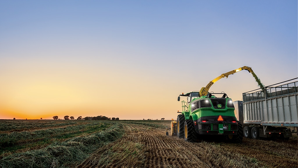 A Self-Propelled Forage Harvester operating in a field during sunset