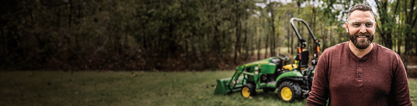 A man hauls wood logs on a 1025R Compact Utility Tractor