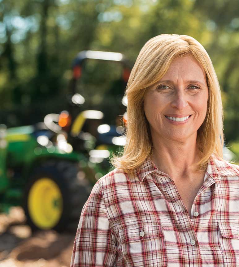 Woman on her property with compact tractor in background