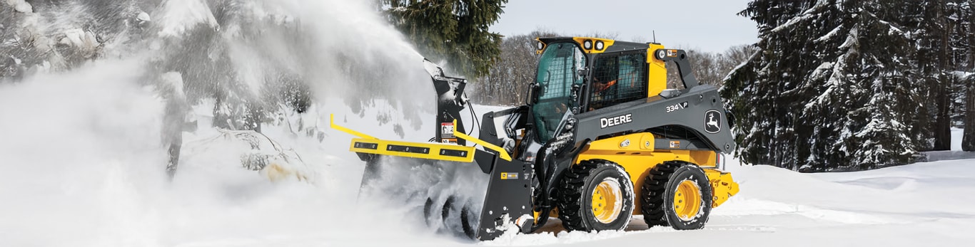 A 334 P-Tier Skid Steer with an SB84S snow blower ejecting snow from its path