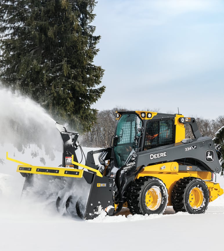 A 334 P-Tier Skid Steer with an SB84S snow blower ejecting snow from its path