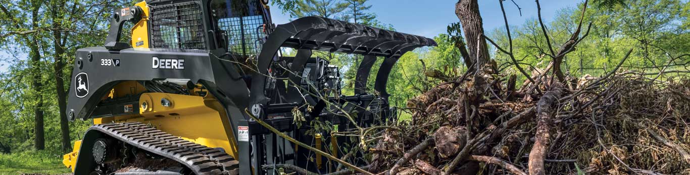 333 P-Tier Compact Track Loader lifts a log with a grapple attachment