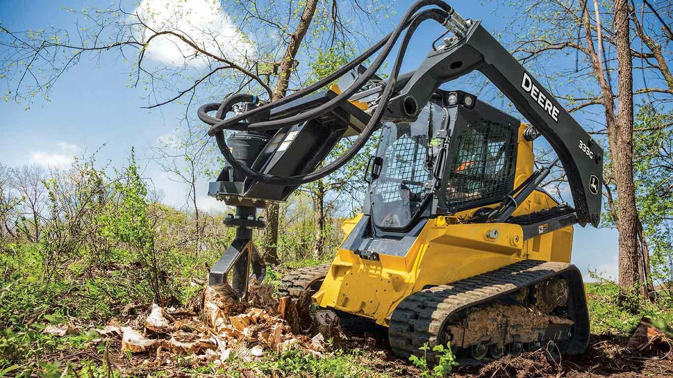 333G Compact Track Loader with a stump shredder attachment working in the woods.