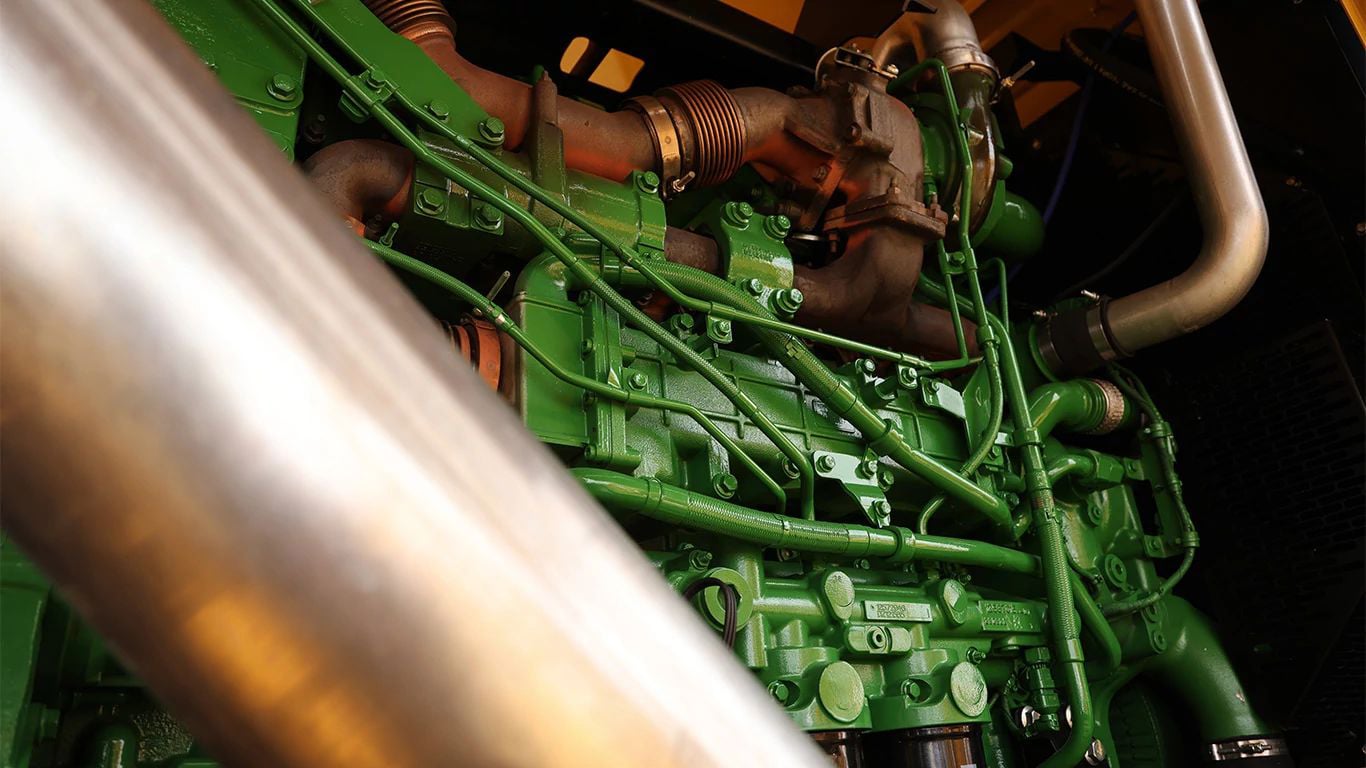 A green John Deere JD18 industrial engine in a Mighty Giant hay grinder