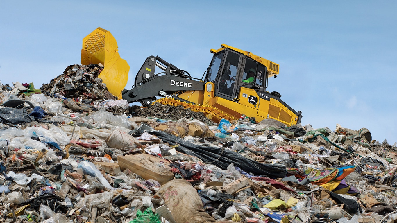 A John Deere 755 K-Tier pushes waste up the hill of a landfill.