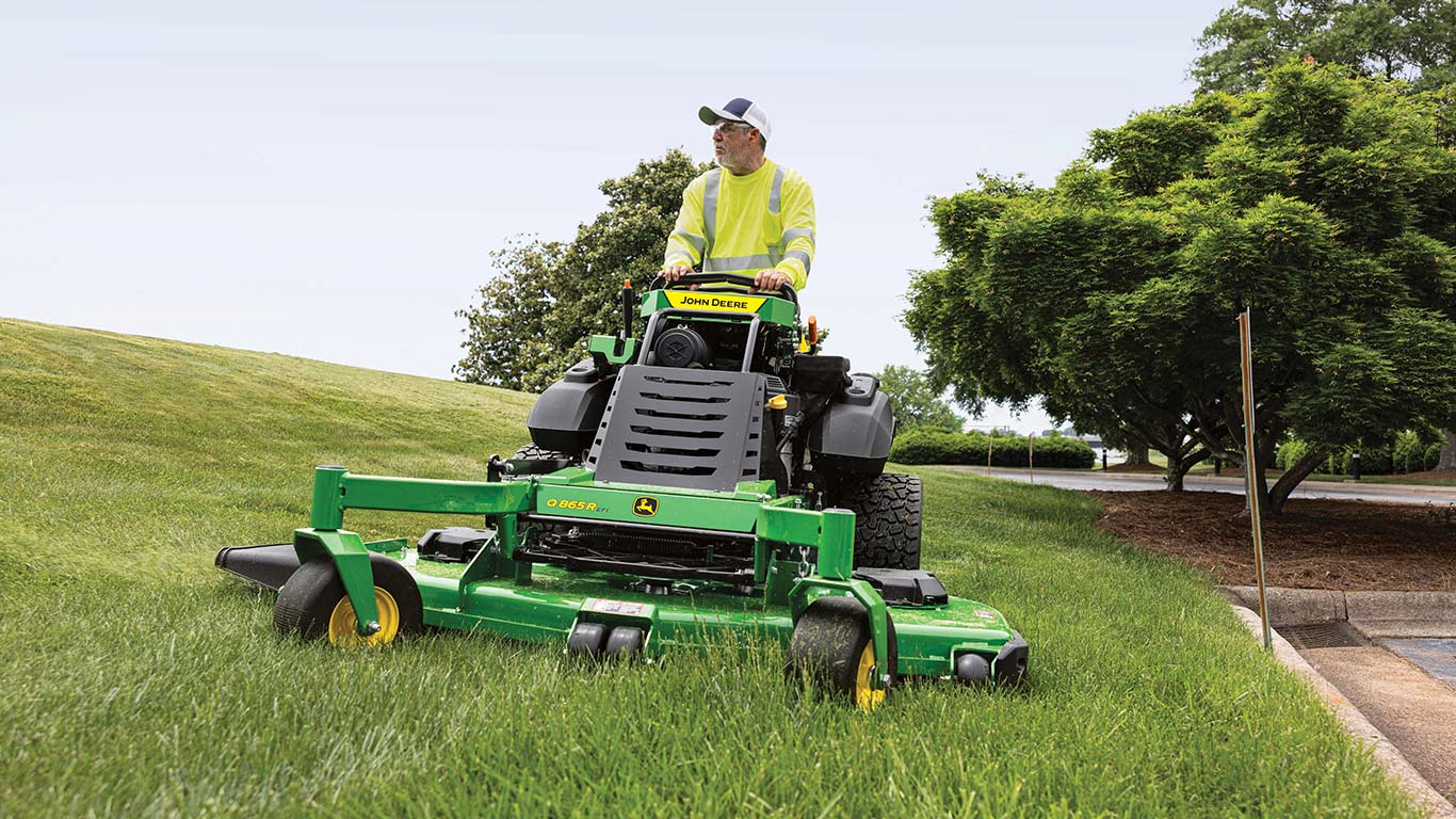 Operator standing on the new Q865R EFI Mower by a parking lot