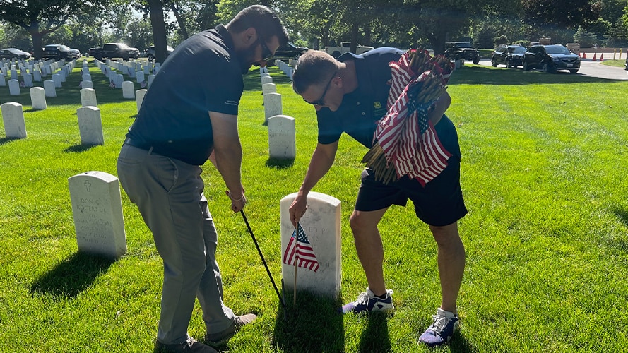 Two people placing United States flags on veterans' graves