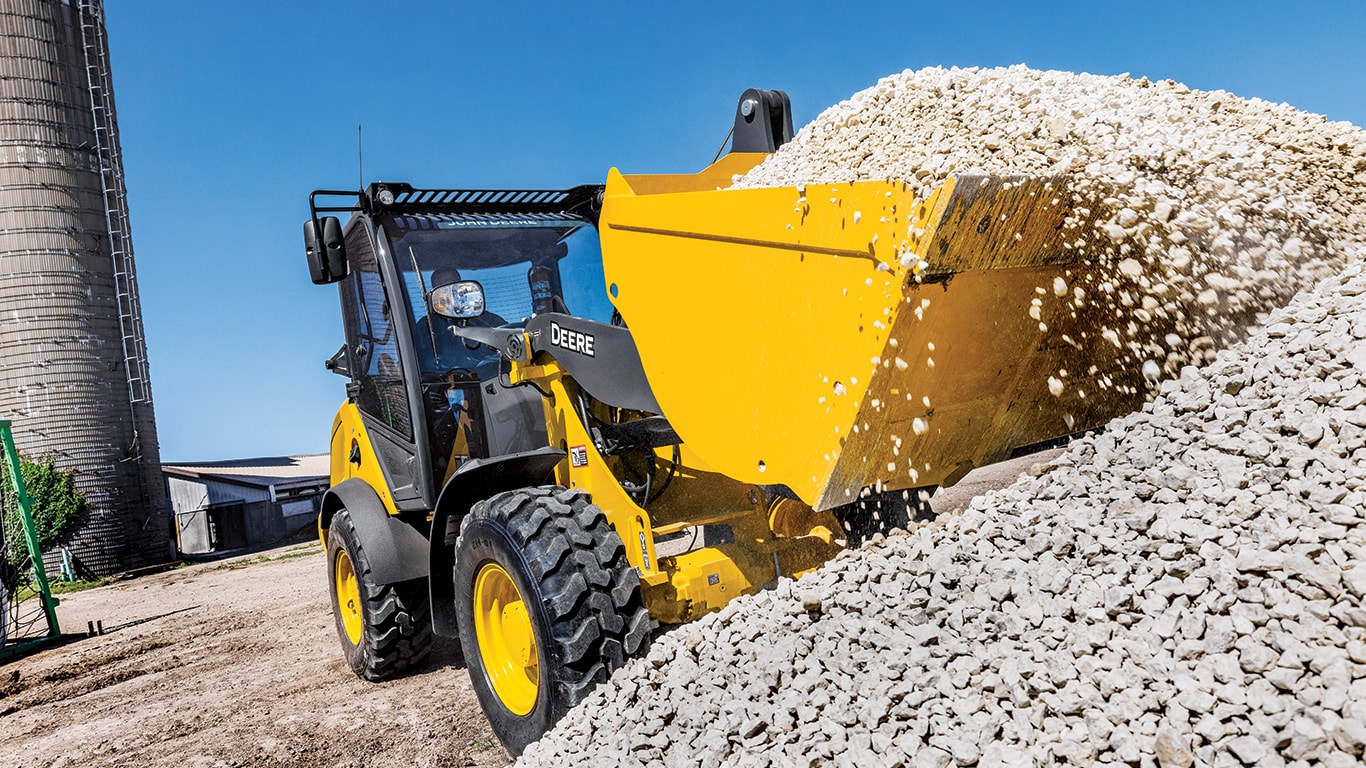 John Deere compact wheel loader lowering a bucketful of gravel