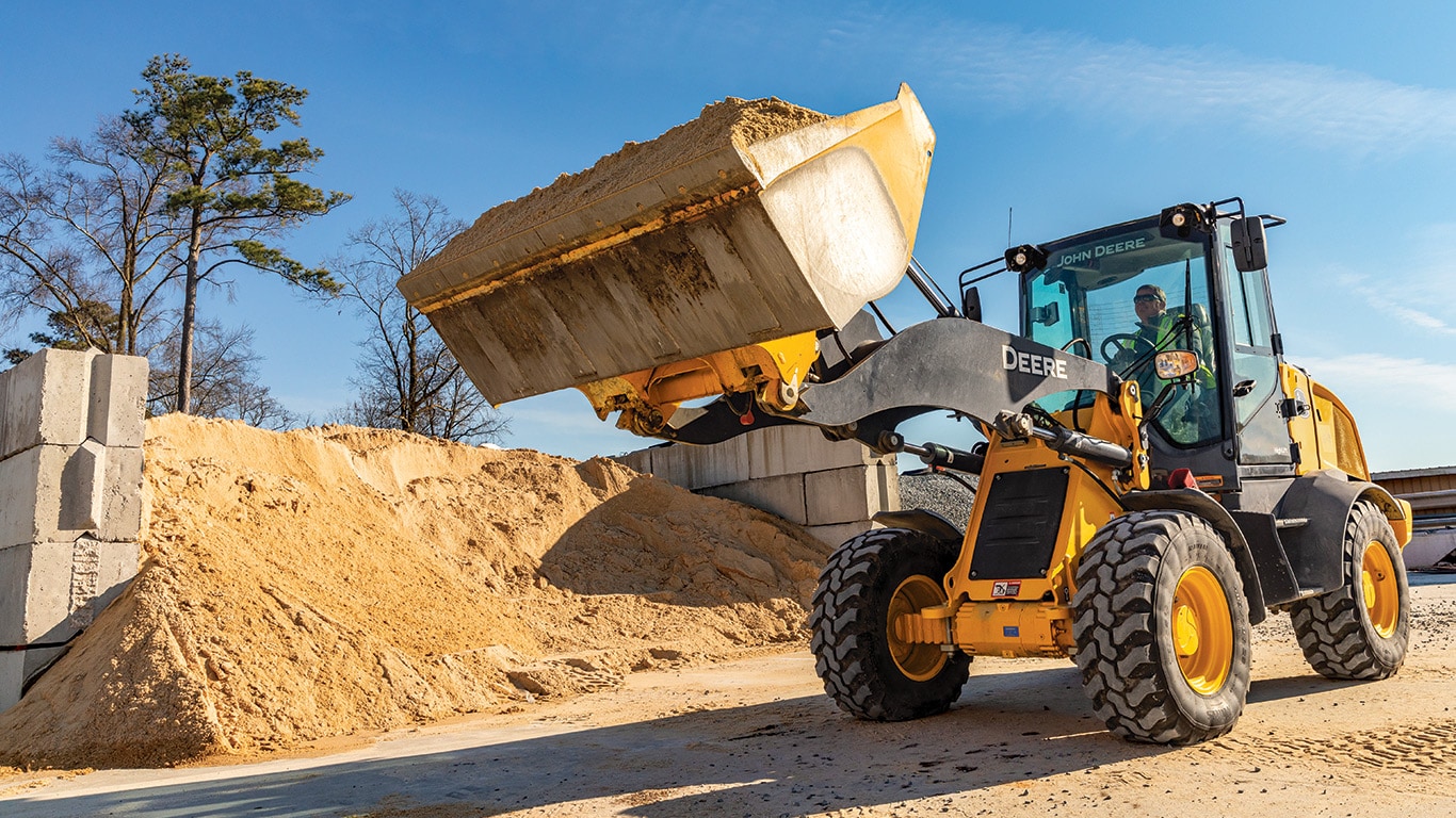 John Deere compact wheel loader moving a bucketful of gravel