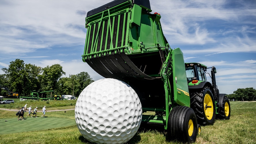 A giant golf ball in front of John Deere equipment on the greens at the John Deere Classic