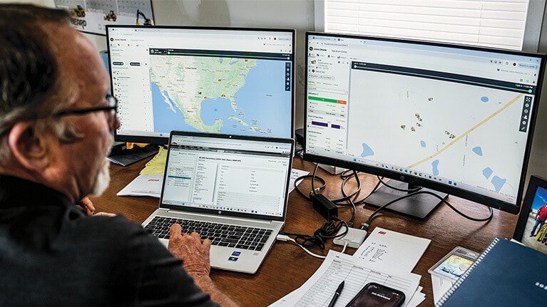 Person on their computer at a desk looking at information on the monitors.