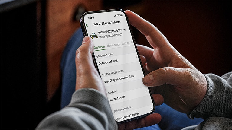 Close-up image of hands holding a cell phone looking at machine information.