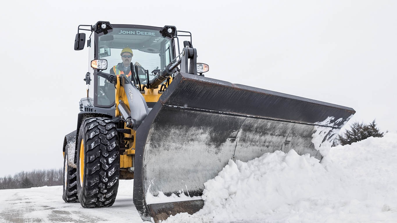 Wheel loader using snow blade to clear snow.