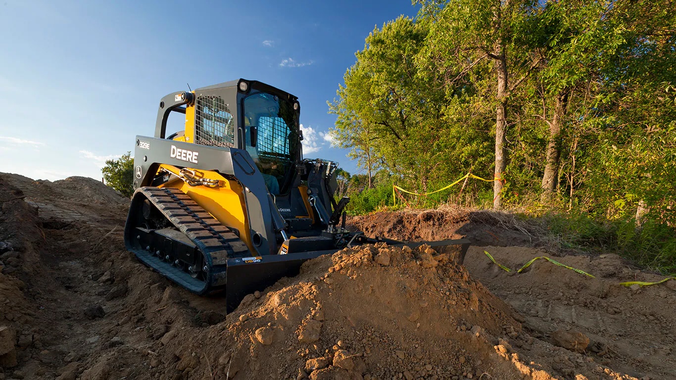 DB96 Dozer Blade attachment on 329E Compact Track Loader pushes dirt on a jobsite.