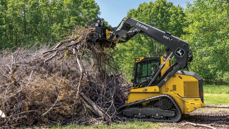 333 P-Tier compact track loader with grapple attachment piling up brush into a pile. (2nd thumbnail)