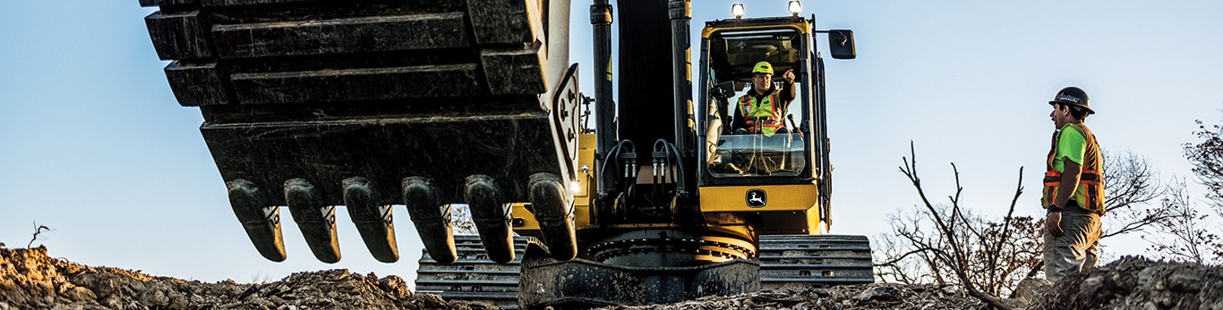 person operating an excavator and another person watching