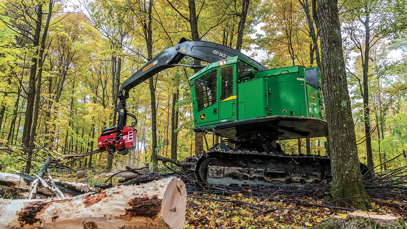 John Deere tracked harvesters working in woods.