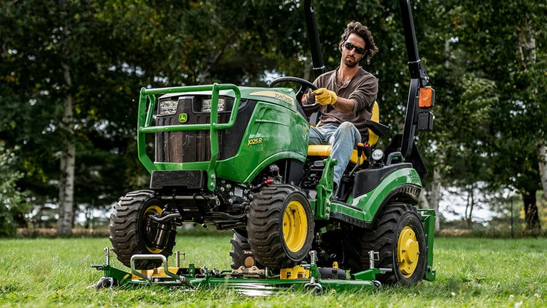 A yard being mowed by a green compact tractor on an AutoConnect mid-mount mowing deck. (15th thumbnail)