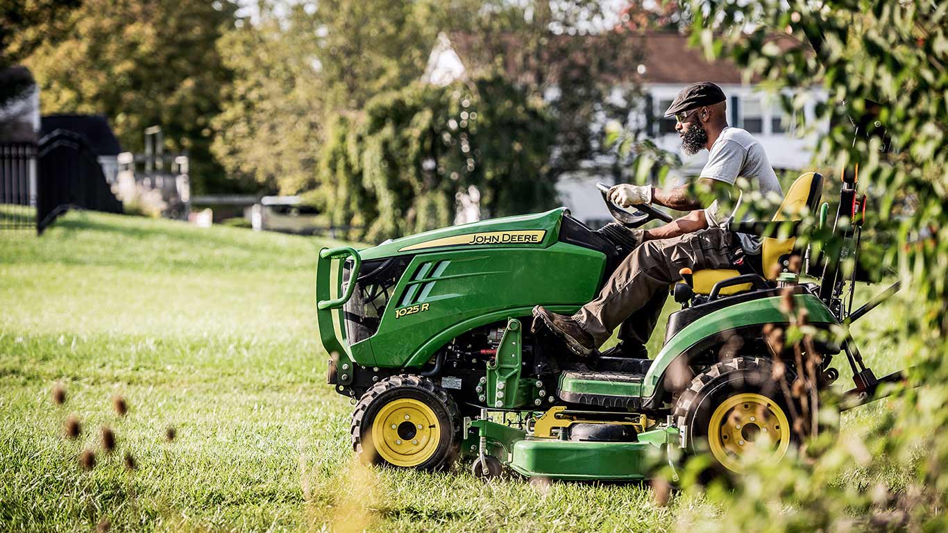 person riding green and yellow compact tractor 1025r person riding green and yellow compact tractor 1025r