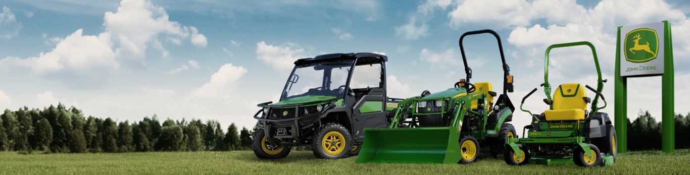 gator utility vehicle, compact tractor and mower in a field with a dealer sign in the background