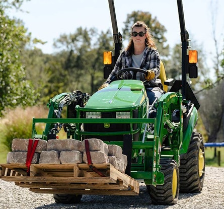 person driving a tractor moving brick pavers