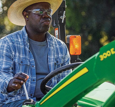 person driving a compact tractor with 300e attachment