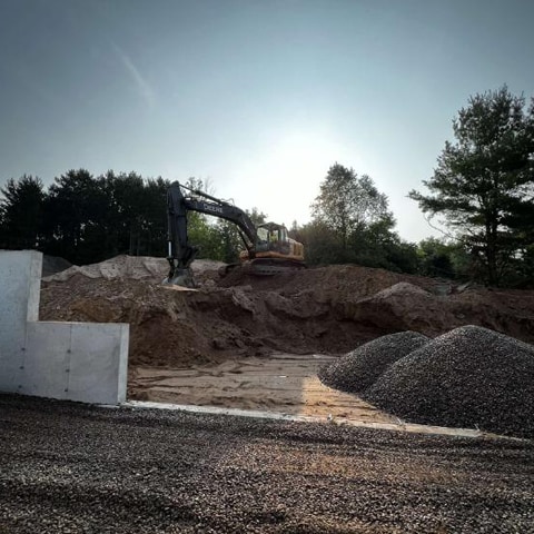 A John Deere Excavator sitting on top of a mound at a construction work site.