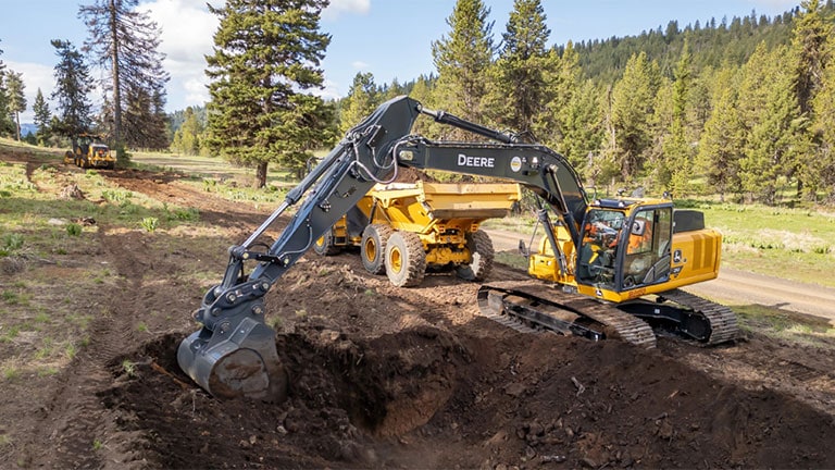 John Deere excavator efficiently digs and loads dirt into a dump truck.