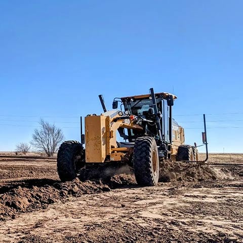 John Deere Motor Grader moves a ridge of dirt