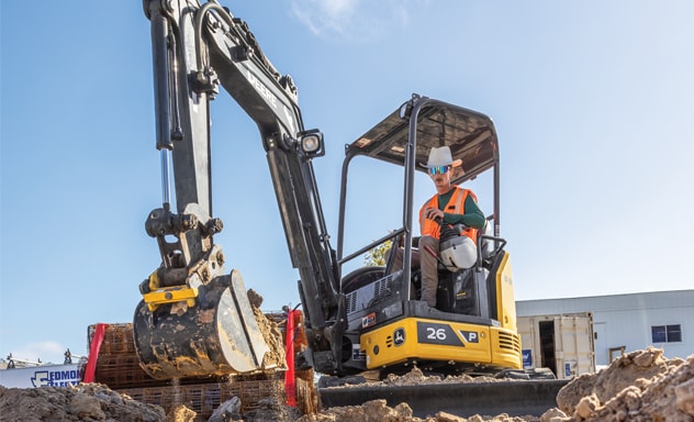 John Deere 26P-Tier Compact Excavator pulls a bucket of dirt from the ground