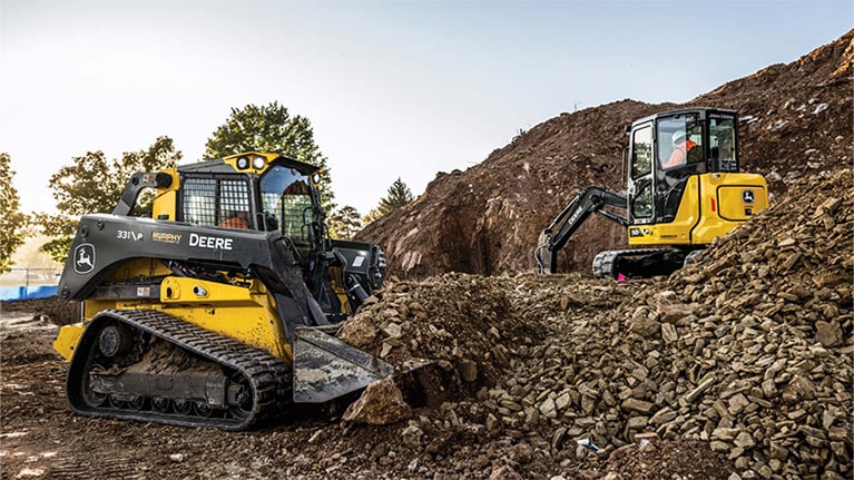 331 P-Tier Compact Track Loader and 50 P-Tier Excavator digging and removing rock from a hillside