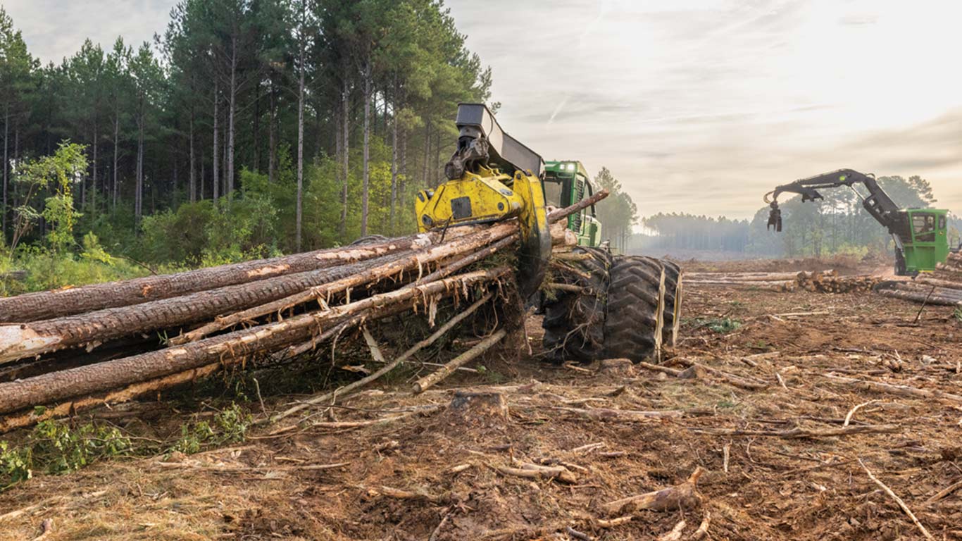 A John Deere 948L-II Grapple Skidder rolls down the ridge, clutching freshly cut tree trunks.