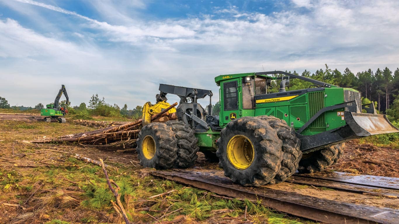 The John Deere 848L-ll Series Skidder equipped with a Grapple squeezes timber as it moves to the landing.