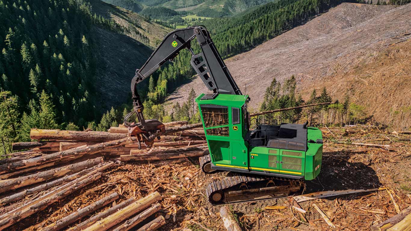 A John Deere 3156G Swing Machine equipped with a Waratah HTH624C strips limbs before piling logs.