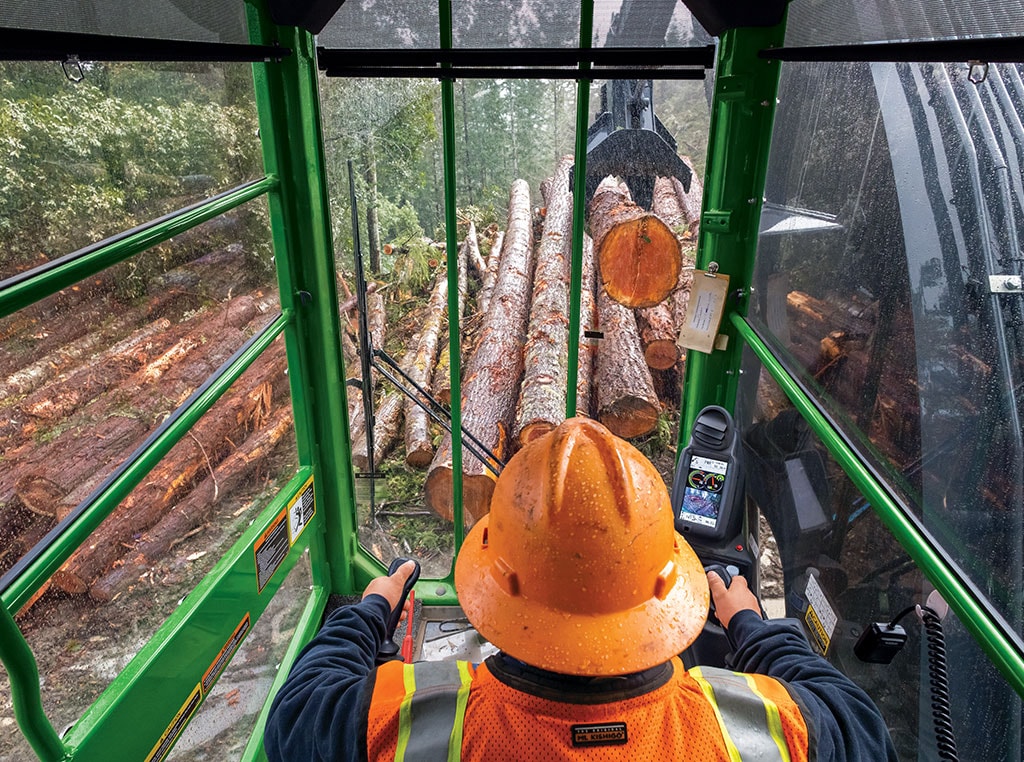 Operator in a John Deere 948L-II Grapple Skidder grabbing logs.