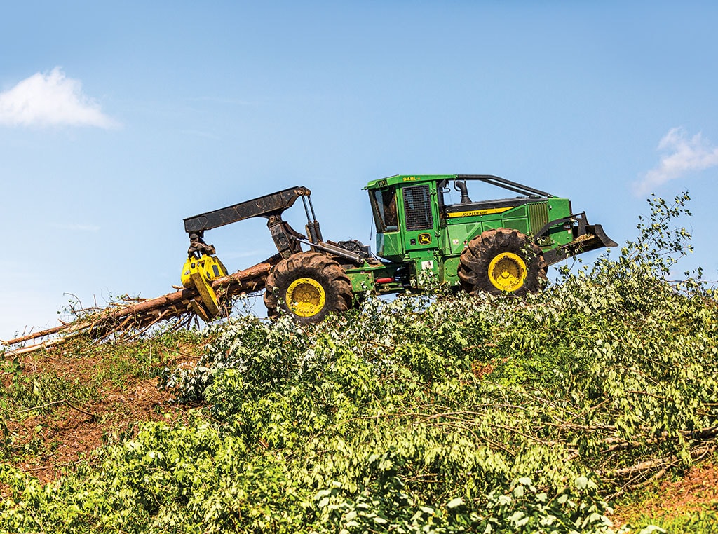 A John Deere 948L-II Grapple Skidder rolls down the ridge, clutching freshly cut tree trunks.