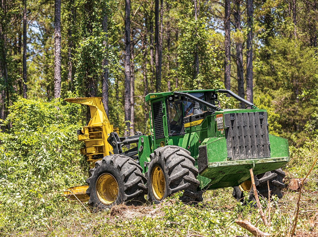 The John Deere 843L-ll approaches a tree before grabbing and cutting with the FD22B felling head.