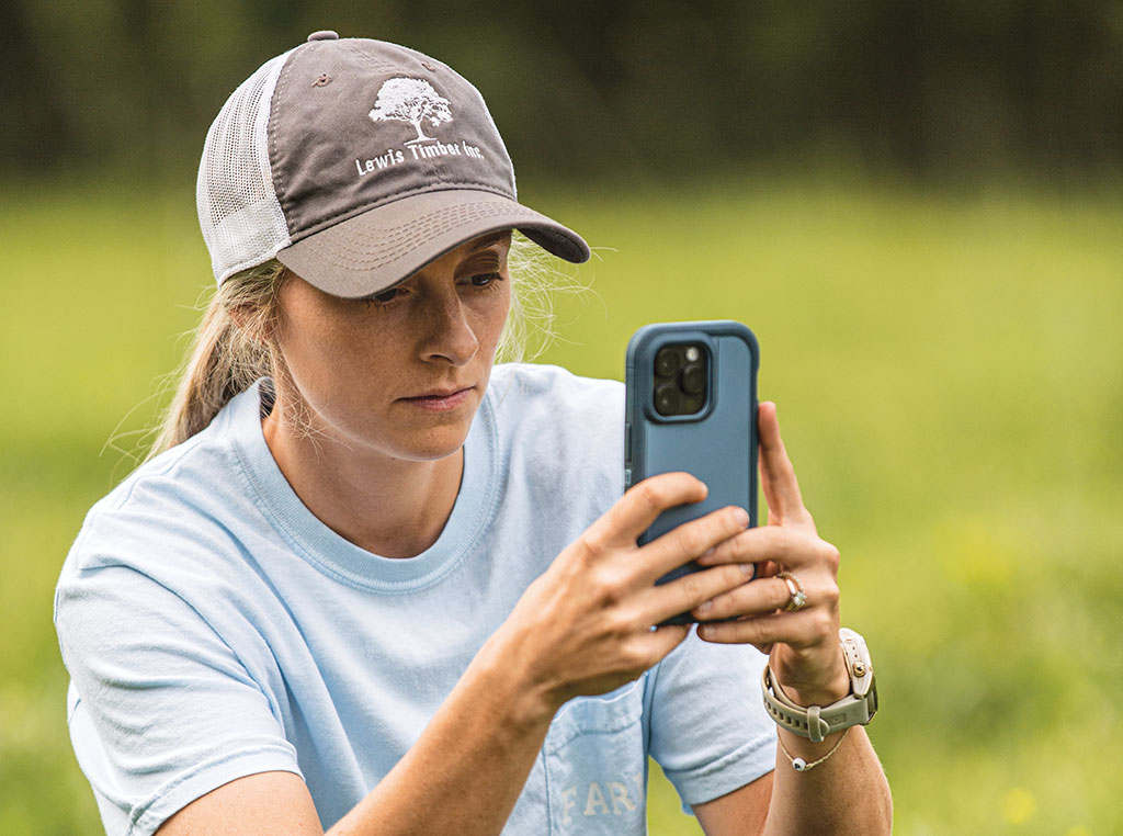 Olivia Lewis crouching down and taking a photo with her phone.