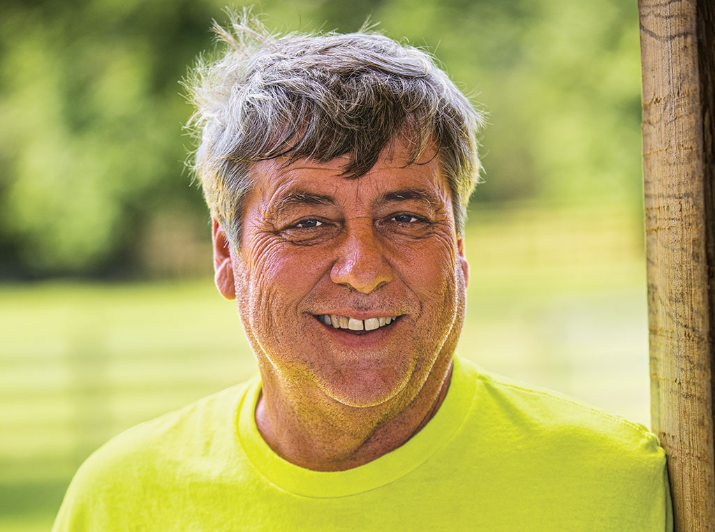 Brian Lewis smiling at camera, leaning against a doorway