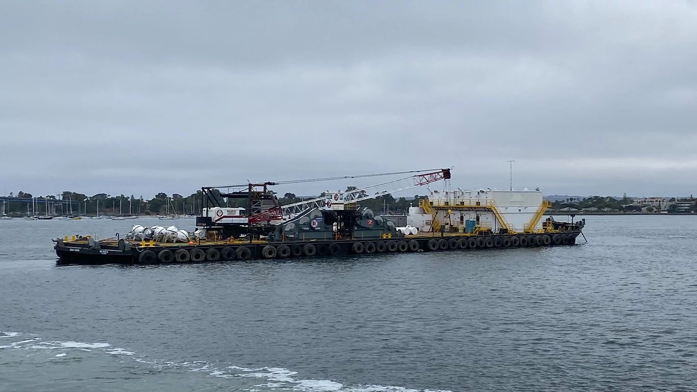 A barge on water with a crane and deck winch powered by a John Deere marine engine